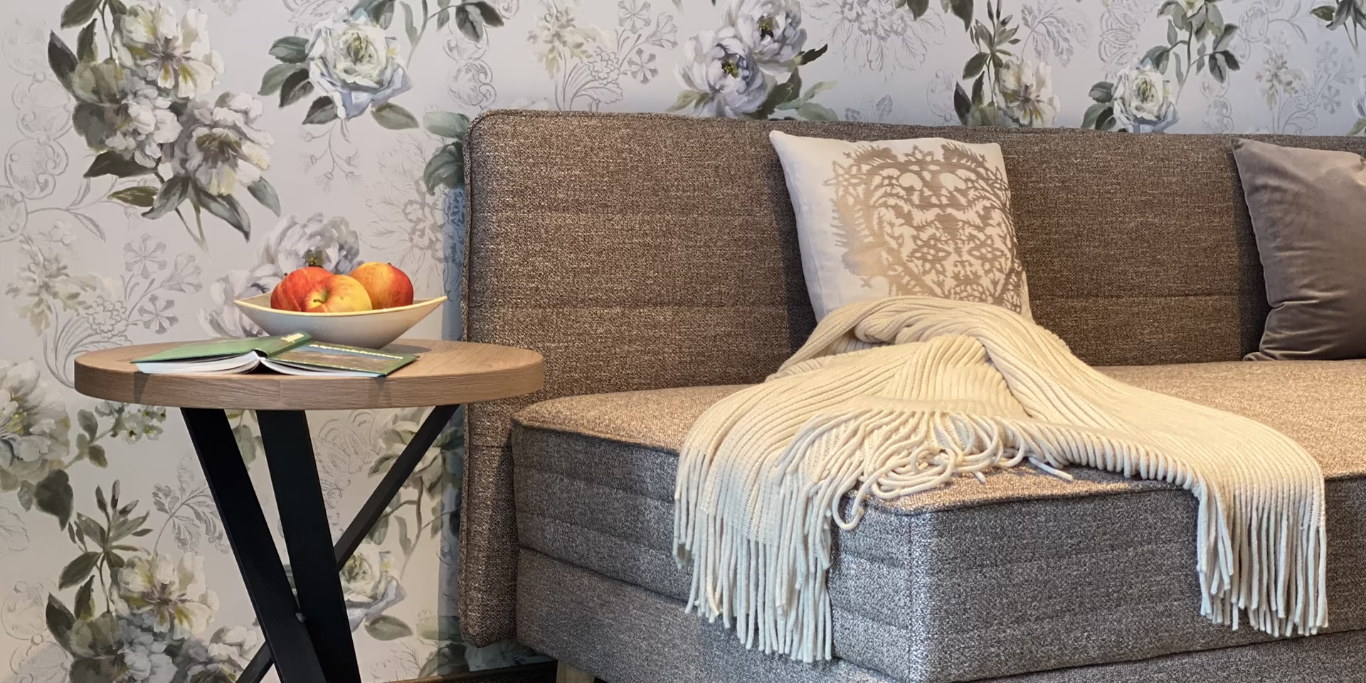 Appartement 5 – stilvoller Wohnbereich zum Entspannen | Pension Eberharter Mayrhofen Gemütlicher Wohnbereich im Appartement 5 der Pension Eberharter in Mayrhofen mit Couch, Decke und Apfelschale auf Beistelltisch.